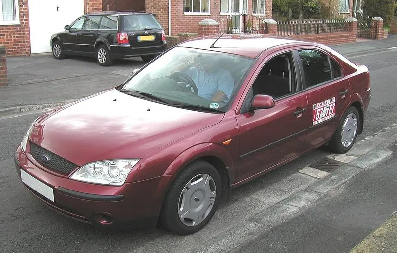 A red private hire saloon car parked on a street